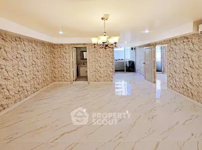 Spacious marble-floored living room with elegant chandelier and open layout.