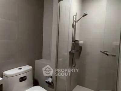 Modern bathroom with sleek shower and toilet in minimalist design.