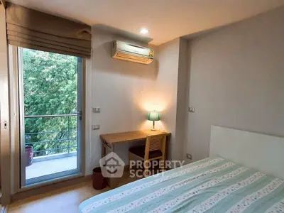 Cozy bedroom with balcony view, featuring a desk and air conditioning, ideal for serene living.