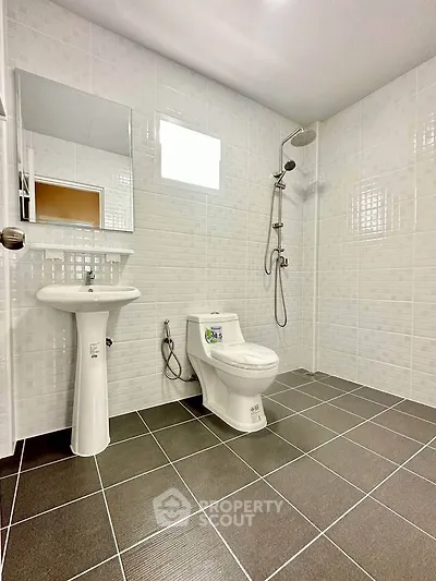Modern bathroom with sleek fixtures and tiled walls, featuring a shower and toilet.