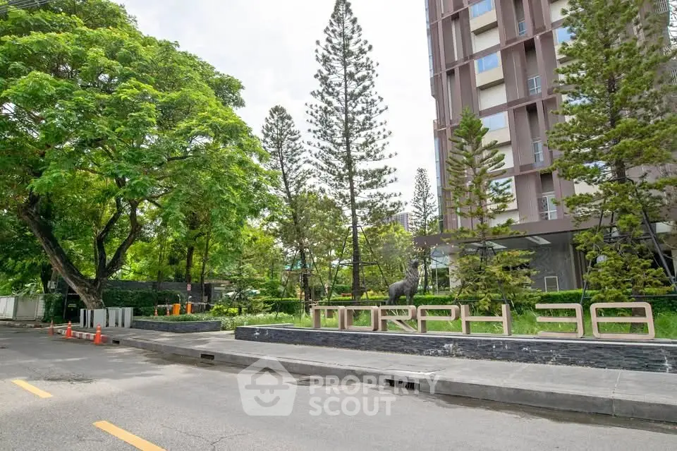 Modern residential building entrance with lush greenery and clear street view.