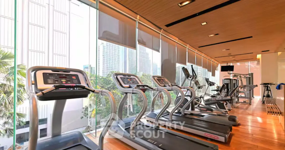Modern gym with city view and state-of-the-art equipment in luxury building.