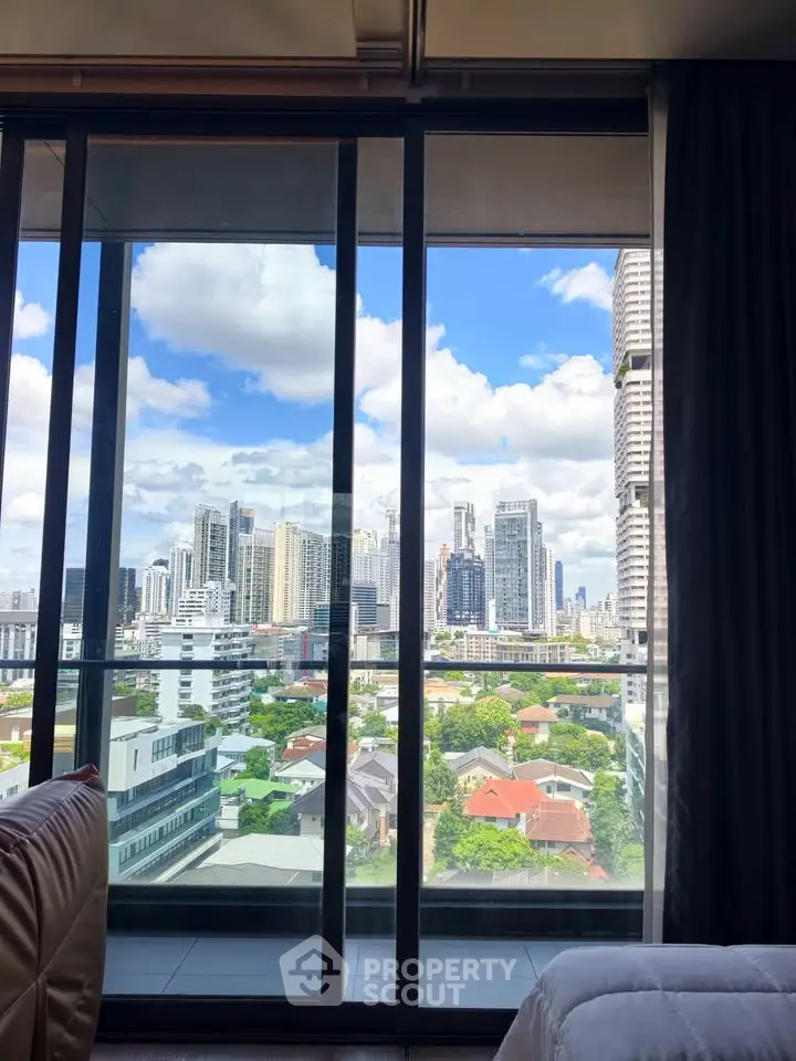 Stunning cityscape view from a modern high-rise apartment window, showcasing urban skyline and blue skies.