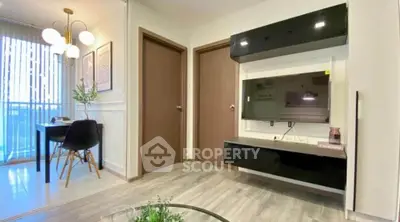Modern living room with sleek TV unit and dining area, featuring elegant lighting and wood flooring.