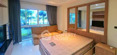 Spacious bedroom with large window and cozy sofa, perfect for relaxation.