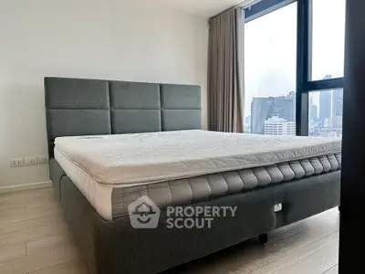 Spacious bedroom with city view, featuring a modern bed and large window for natural light.