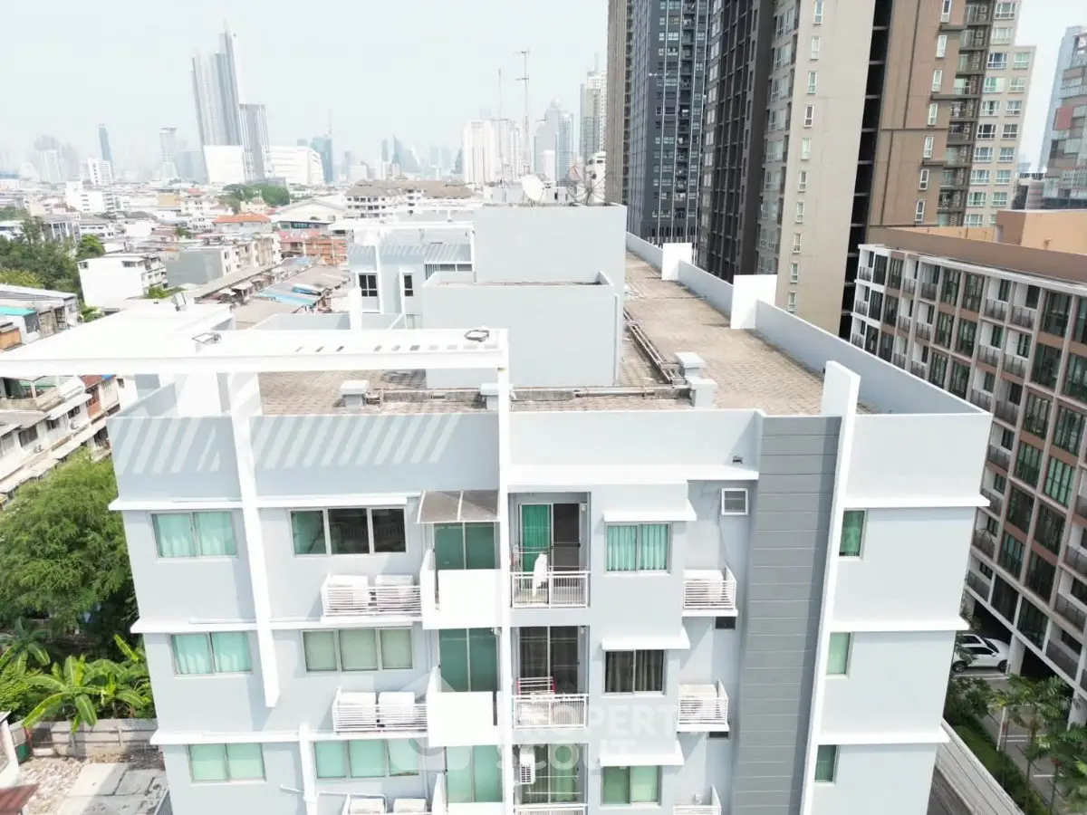 Modern urban apartment building with city skyline view, showcasing contemporary architecture and rooftop area.