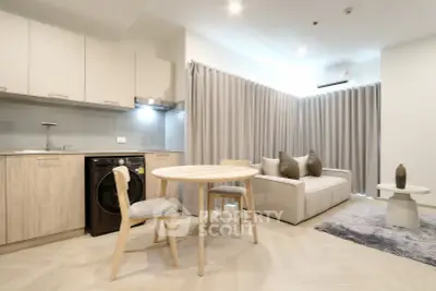Modern open-plan living room with kitchen, featuring sleek furniture and neutral tones.