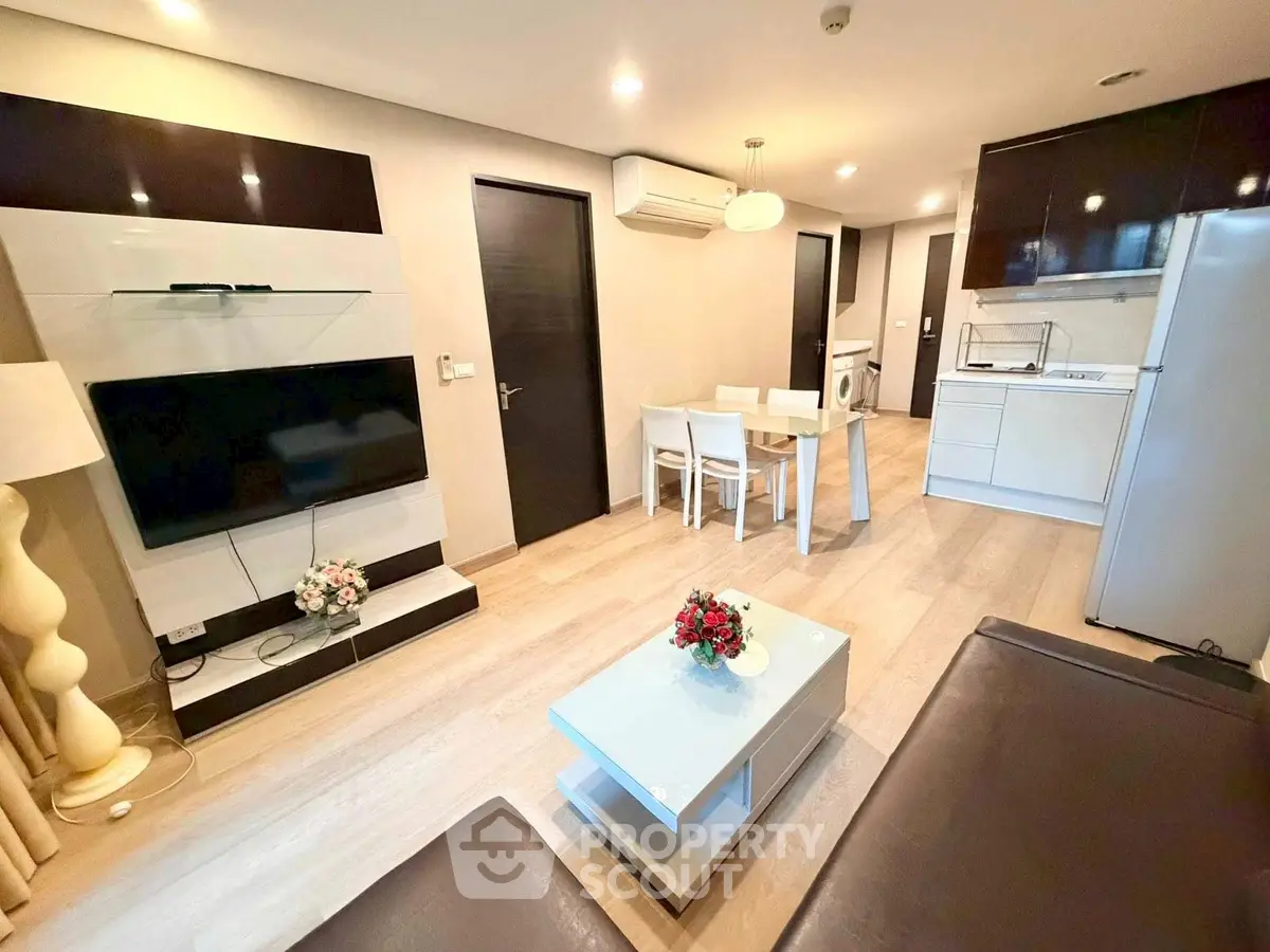 Modern living room with open kitchen, sleek furniture, and ambient lighting for a cozy atmosphere.