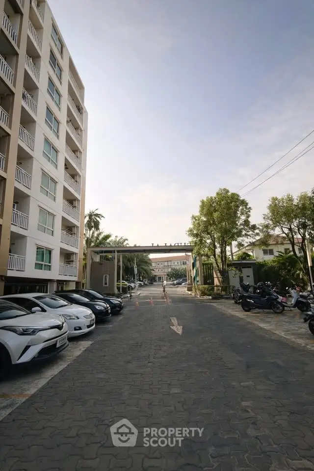 Modern apartment building with spacious parking area and lush greenery, ideal for urban living.