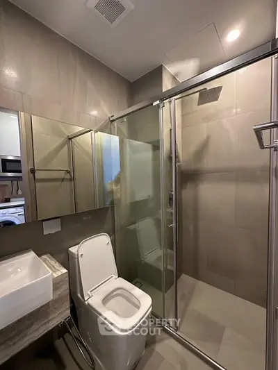 Modern bathroom with glass shower and sleek fixtures in a contemporary apartment.