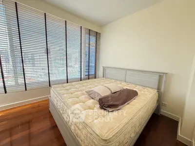 Bright bedroom with large windows and wooden flooring in modern apartment.