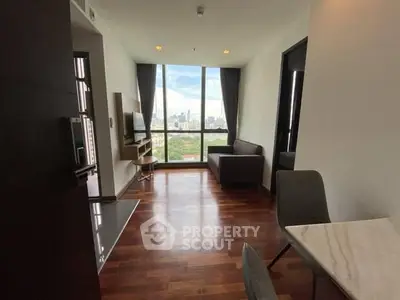 Modern living room with city view, hardwood floors, and sleek furniture.