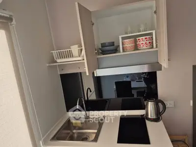 Modern compact kitchen with open cabinets, electric stove, and sleek sink design.