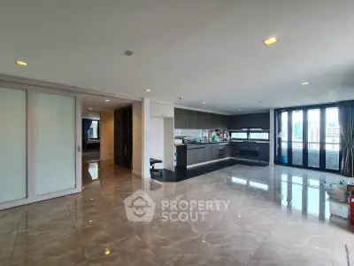 Spacious open-plan living room with modern kitchen and city view, featuring glossy marble floors and ample natural light.