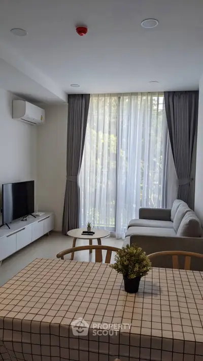Modern living room with large window, stylish furniture, and natural light.