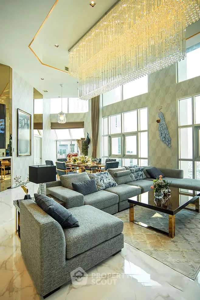 Luxurious living room with high ceilings, elegant chandelier, and modern decor in a spacious open layout.