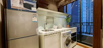 Modern kitchen with stainless steel fridge and washing machine, city view balcony.