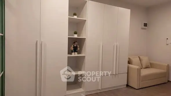 Modern minimalist living room with white built-in storage and cozy beige sofa.
