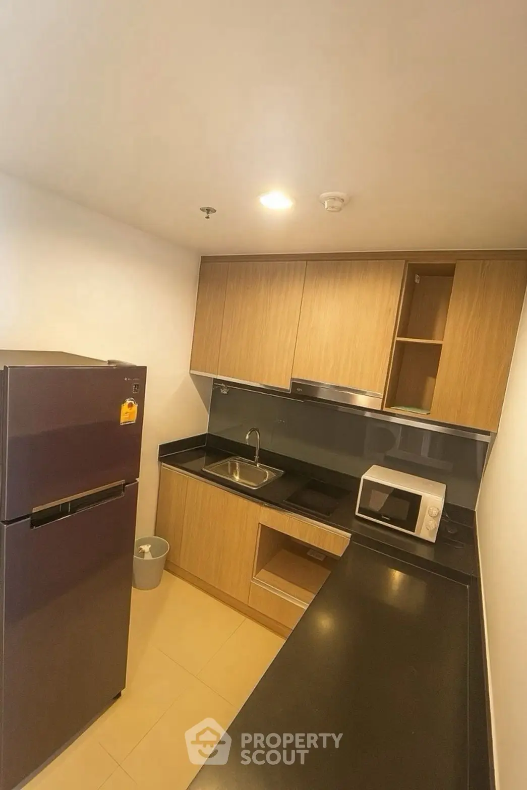 Modern kitchen with sleek black countertops, wooden cabinets, and stainless steel appliances.