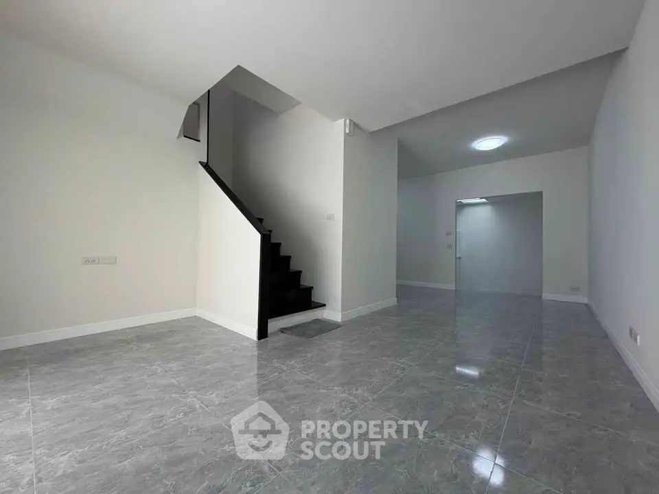 Spacious modern interior with sleek staircase and glossy tiled flooring, perfect for contemporary living.