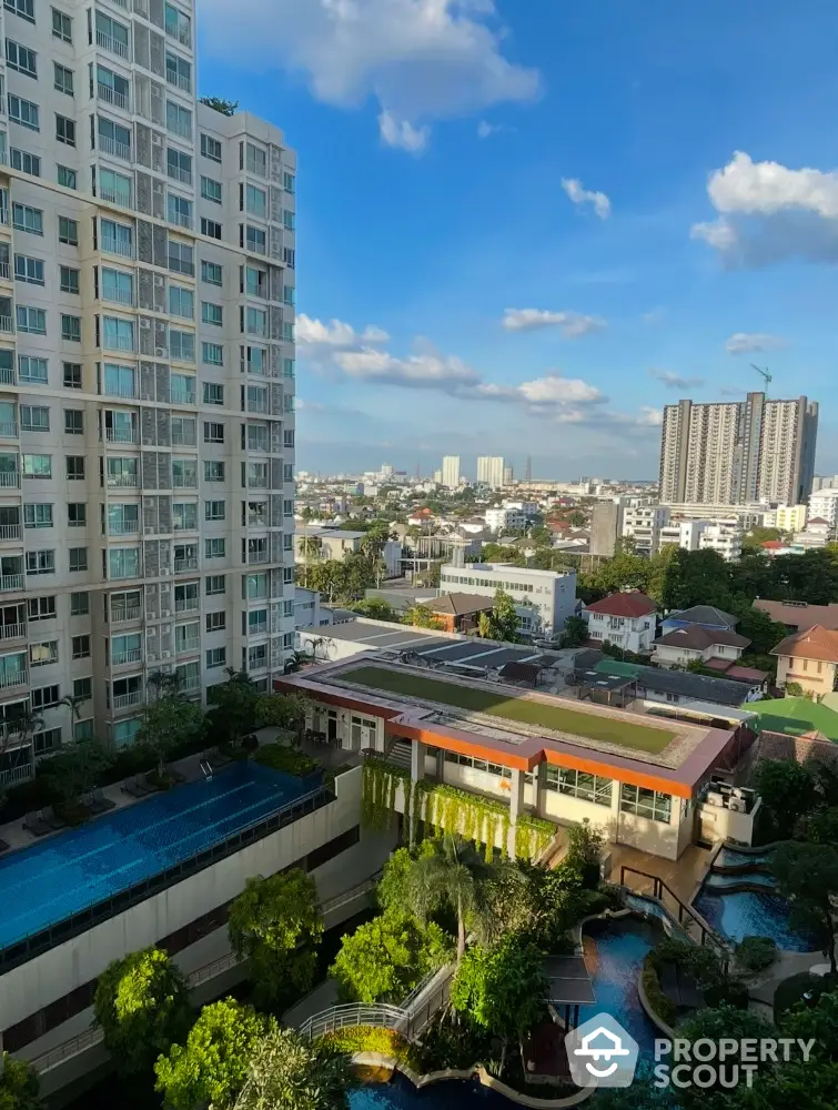 Stunning cityscape view from high-rise apartment with lush greenery and pool area