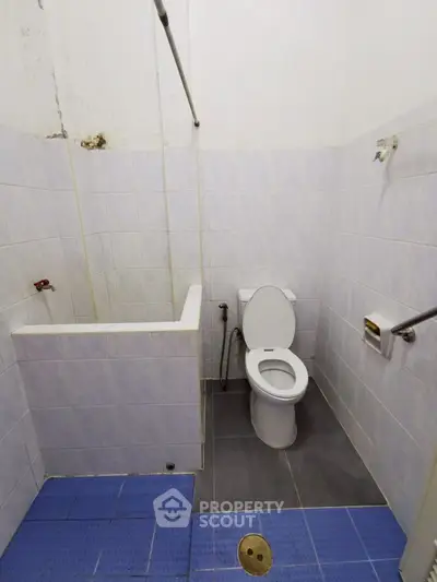 Compact bathroom with tiled walls and floor, featuring a toilet and shower area.