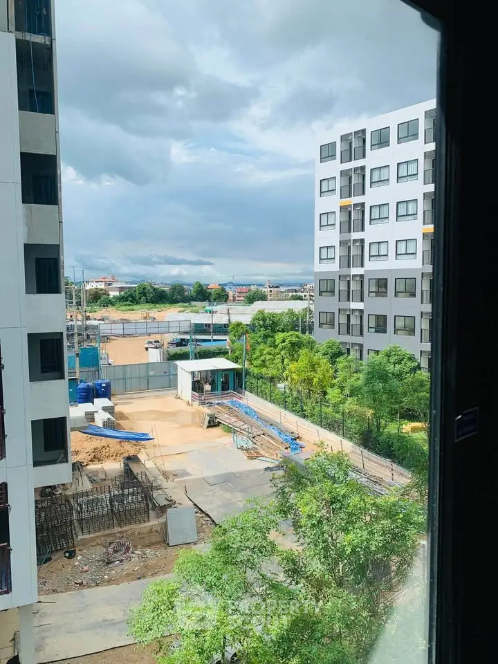 Modern urban apartment view with construction site and greenery.