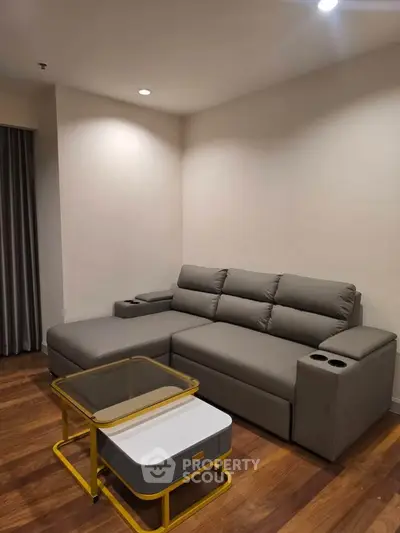 Modern living room with sleek gray sofa and stylish coffee table on wooden flooring.