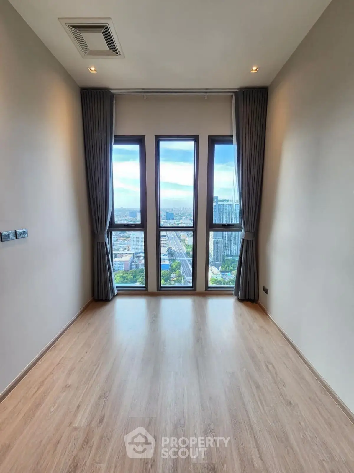 Spacious room with floor-to-ceiling windows offering stunning city views, perfect for modern living.