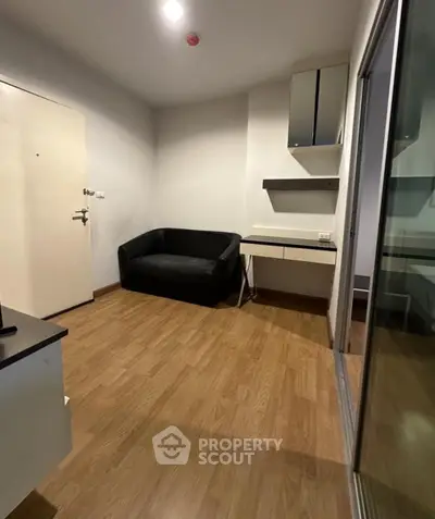 Cozy small living room with wooden flooring and modern black sofa