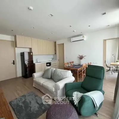 Modern living room with open kitchen, cozy seating, and stylish decor in a contemporary apartment.