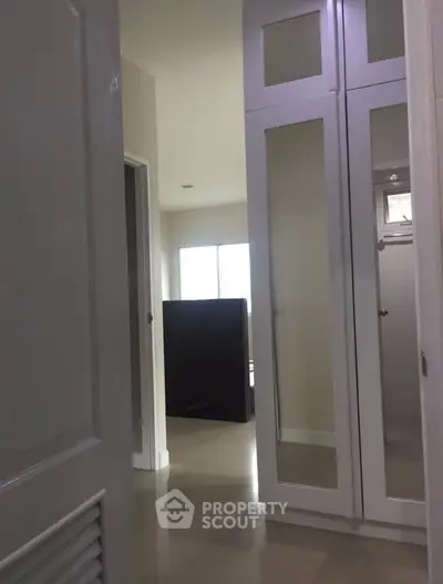 Spacious hallway with mirrored closet doors and natural light in modern home.