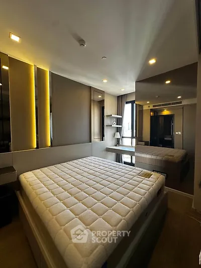 Modern bedroom with stylish lighting and large mirror reflecting elegant decor.