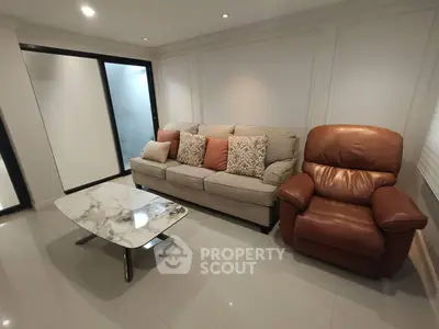 Modern living room with stylish sofa and armchair, featuring a sleek marble coffee table.