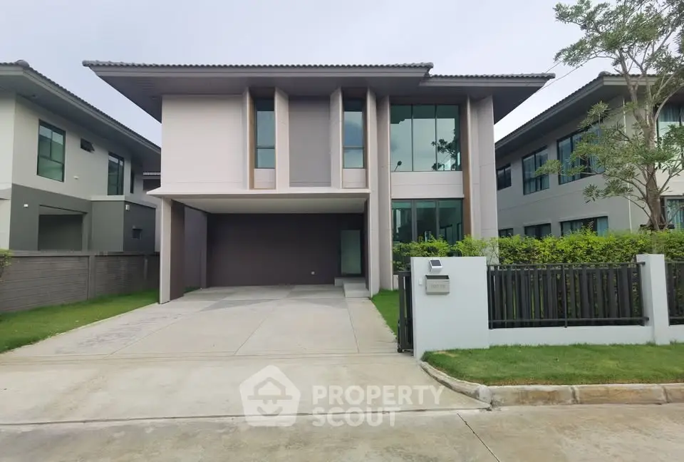 Modern two-story house with sleek design and spacious driveway in a suburban neighborhood.