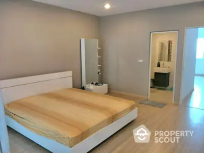 Spacious bedroom with modern minimalist design, featuring a large bed, sleek wardrobe, and warm wooden flooring, leading to an en-suite bathroom.