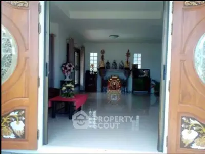 Spacious living room with elegant wooden doors and polished floors, perfect for a serene home environment.