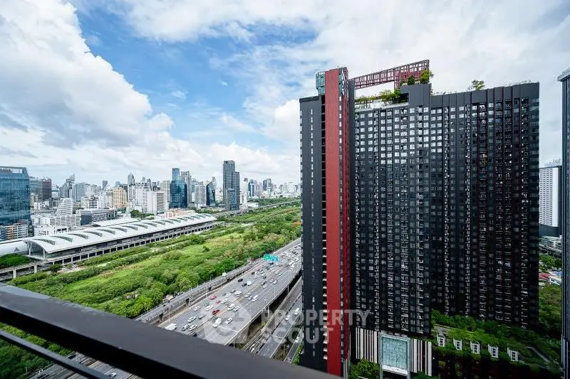 Stunning cityscape view from a high-rise balcony overlooking urban skyline and lush greenery.