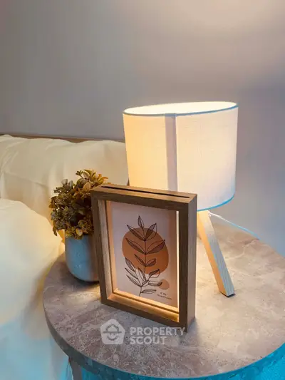 Cozy bedroom nightstand with modern lamp and decorative frame.