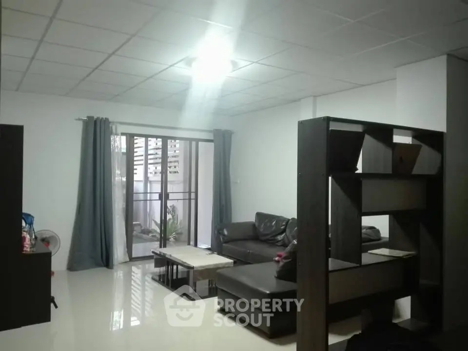 Spacious living room with modern furniture and large windows leading to a balcony.