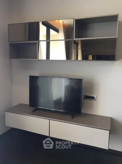 Modern living room with sleek TV stand and mirrored wall cabinets