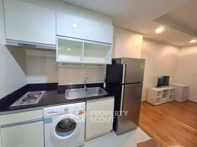Modern kitchen with washing machine and stainless steel fridge in compact apartment