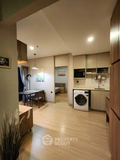 Modern apartment interior with open kitchen and cozy dining area, featuring a washing machine and stylish decor.