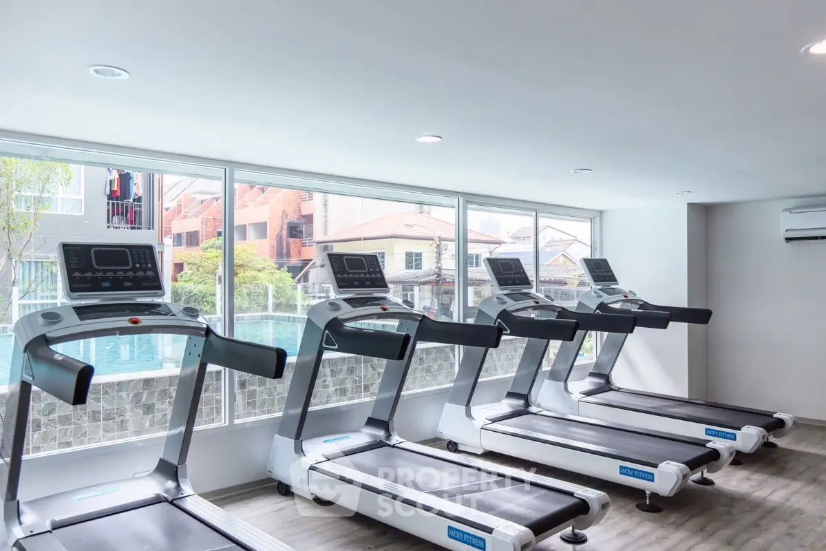 Modern gym with treadmills overlooking a pool, perfect for fitness enthusiasts.