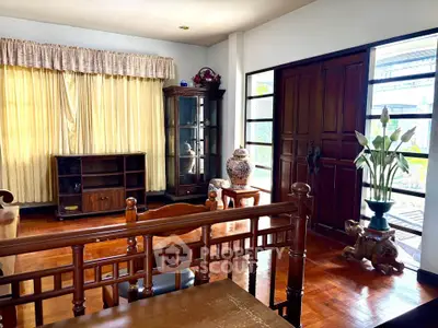 Charming living room with wooden furniture and large windows for natural light.