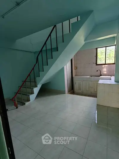 Spacious interior with staircase and tiled flooring, featuring a compact kitchen area.