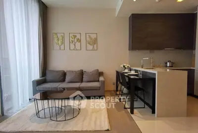 Modern living room with open kitchen, stylish decor, and natural light.