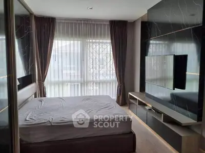 Modern bedroom with sleek TV setup and large window with curtains