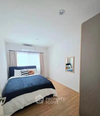 Cozy bedroom with modern decor and natural light, featuring a comfortable bed and stylish wooden flooring.